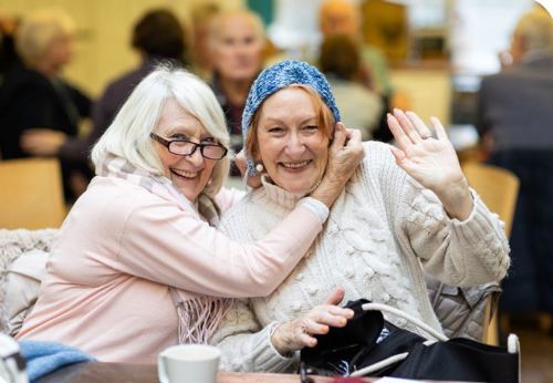 Two older people smiling and waving