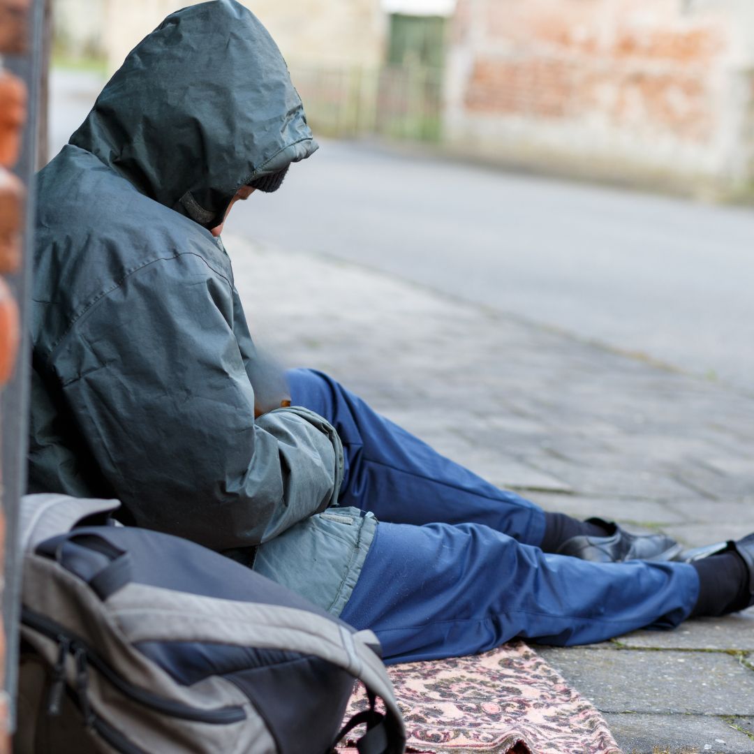 Homeless person sitting on pavement