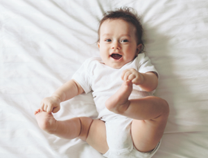 baby smiling on white blanket