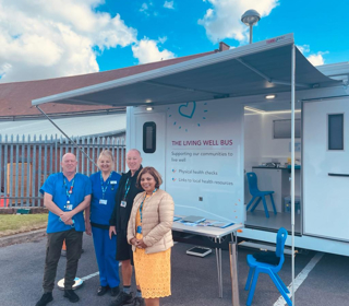 Living Well Bus team standing in front of the  vehicle