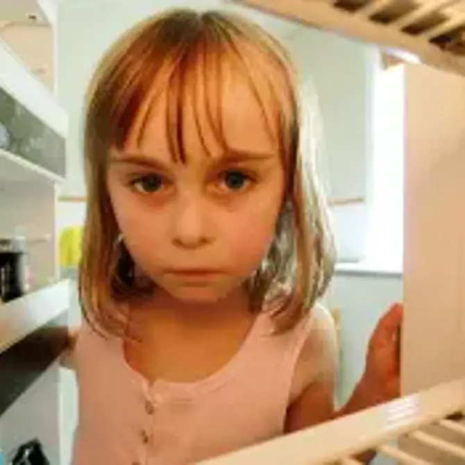 Sad looking child peering into empty fridge